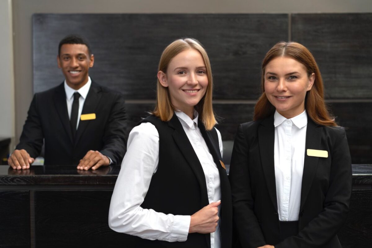 Hostess (fotografie cu 3 angajati zambitori care intampina clientii)